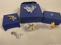 Five Swarovski crystal miniature figurines displayed with three original blue Swarovski boxes, showing lot contents and condition