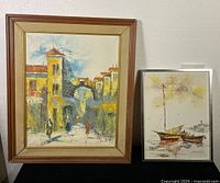 Framed oil on canvas paintings signed Adriano Marcello and McKie, shown side by side on black cloth with visible frame wear