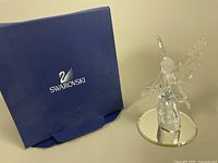 Blue Swarovski box beside the crystal angel figurine on a round mirrored display base, showing the overall lot contents.