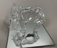 Clear Swarovski Austrian crystal elephant figurine viewed from a side angle on the mirrored display base, showing faceted body and clear tusks.