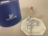 Crystal seal figurine balancing pink and yellow juggling balls atop nose, with mirrored base and Swarovski box.