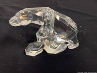 Front and side view of clear faceted polar bear figurine on black surface
