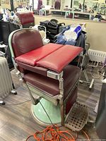 Front view of burgundy vinyl chair with booster bars installed on chrome arms and mint green base.