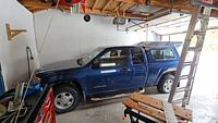 Side view of blue GMC Canyon extended cab with Leer shell inside garage