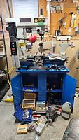 Full view of Craftex lathe/mill combo on blue stand with accessories laid out on floor
