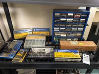 Photo of black shelving unit with multiple plastic organizer drawers and several sealed hardware kits including lock washers, hex screws, and more