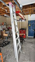 Full view of the 8ft aluminum step ladder in a garage setting, showing its height and step layout.