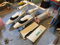 Two white C-WIND Seawind fuselages on carpet with detached wings and stands