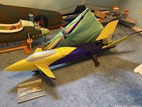 Overview of purple and yellow jet fuselage with detached wings and landing gear