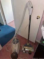 Full view of the TriStar canister vacuum cleaner with hose, metal wand, Turbo Brush cleaning head, and attachments on a carpeted floor.