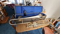 Open case showing trombone placed inside alongside folding stand parts