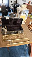 Lot contents displayed on table: trombone body, slide, mouthpiece and open case interior