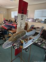Front view of fuselage on stand showing engine, nose art and wing panel behind