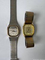Photo of two vintage men's Cardinal watches side by side; silver-tone watch has a link bracelet strap, gold-tone watch has an expansion band and is missing the winding crown.