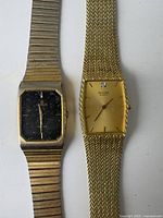 Two vintage men's quartz wristwatches: Lorus with black dial and Bulova with gold dial, both gold-tone metal bands.