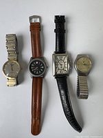 Four men's wristwatches laid out side by side showing different band types and dial styles.