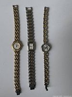 Photo of three vintage women's wristwatches laid flat showing metal link bracelets and watch faces.