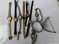Photo showing nine vintage women's wristwatches in a variety of metal and leather bands with different dial shapes and colors.