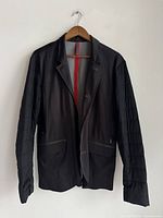 Full front view of black men's blazer on hanger showing design, lapels, and front pockets.