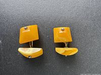 Front view of two cufflinks showing amber pieces with metal pins and connection