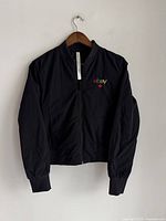 Front view of black Lululemon women's jacket hung on a hanger showing full zip and collar.