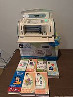 Overall shot showing Cricut Create machine on its original box with seven cartridge boxes arranged in front
