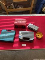 Closed cases of various hole saw and drill bit sets with a large yellow hole saw at right