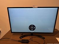 LG 32-inch monitor powered on showing on-screen display menu confirming working condition. Black stand and slim bezel design visible.
