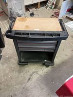 Front view of the black Mastercraft rolling storage and tool cart with two drawers and wooden top.