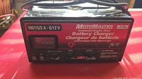 Front view of the Motomaster battery charger showing branding, amperage ratings, and model number 11-1571-8.