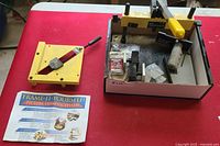 Yellow plastic miter box and instruction sheet on red table.