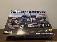 Top view of the Revell 1:25 scale Peterbilt 359 Wrecker model kit box showing colorful artwork of the blue wrecker truck and branding information.