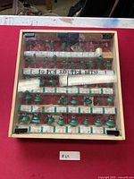 Top view of closed wooden case containing 50 router bits with tungsten carbide tips for woodworking. The case has a clear acrylic lid with text '50 PCS ROUTER BITS TUNGSTEN CARBIDE TIPPED FOR WOOD WORKING'.