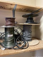 Four wire spools holding various cables on a shelf.