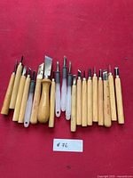 Full set of 19 woodworking tools laid out on red background showing mainly wood handles and few clear plastic handles with metal carving and lathe blades.