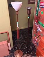 Two floor lamps side by side, one with white milk glass shade and wooden accent, one metal torchère base without shade