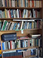 Three-shelf view of assorted hardcover and paperback books on wooden bookshelf