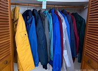 Full view of 11 assorted men’s jackets hung on closet rod, showing variety of colors and styles