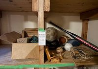Overview shelf with miscellaneous sports equipment including balls, bat, gloves, and shoes on wooden shelving.