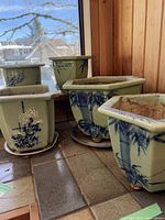 Four hexagonal and square ceramic planters together on floor with hand-painted bamboo and chrysanthemum motifs in blue and white on green glaze