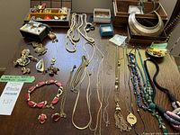 Overview of assorted necklaces, bracelets, earrings and brooches laid on table.