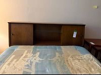 Front view of headboard showing sliding wooden doors and central glass shelf