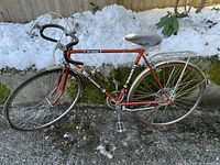 Full side view of the red vintage Eliminator Mark II 10-speed bike outdoors on pavement with snow in background.