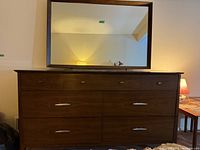 Full front view of brown wood dresser topped by matching framed mirror
