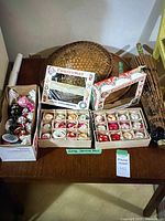 Overview of ornaments, two boxed sets, loose ornaments in box, two bamboo hats and folded floral parasol on table