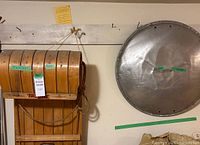 View of wooden TruLine toboggan and metal saucer sled hanging on wall, showing the size and condition of both items.