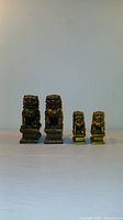 Front view of two pairs of gold resin Chinese guardian lions arranged from largest to smallest.