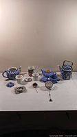 Full lot of four porcelain teapots and assorted metal tea diffusers displayed on white surface