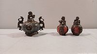 Wide shot showing one incense holder with guardian lion lid and dragon handles on the left, two matching reddish stone guardian lion figurines on the right.