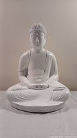 Front view of white ceramic Buddha statue showing meditative seated pose and detailed textured curls on head.